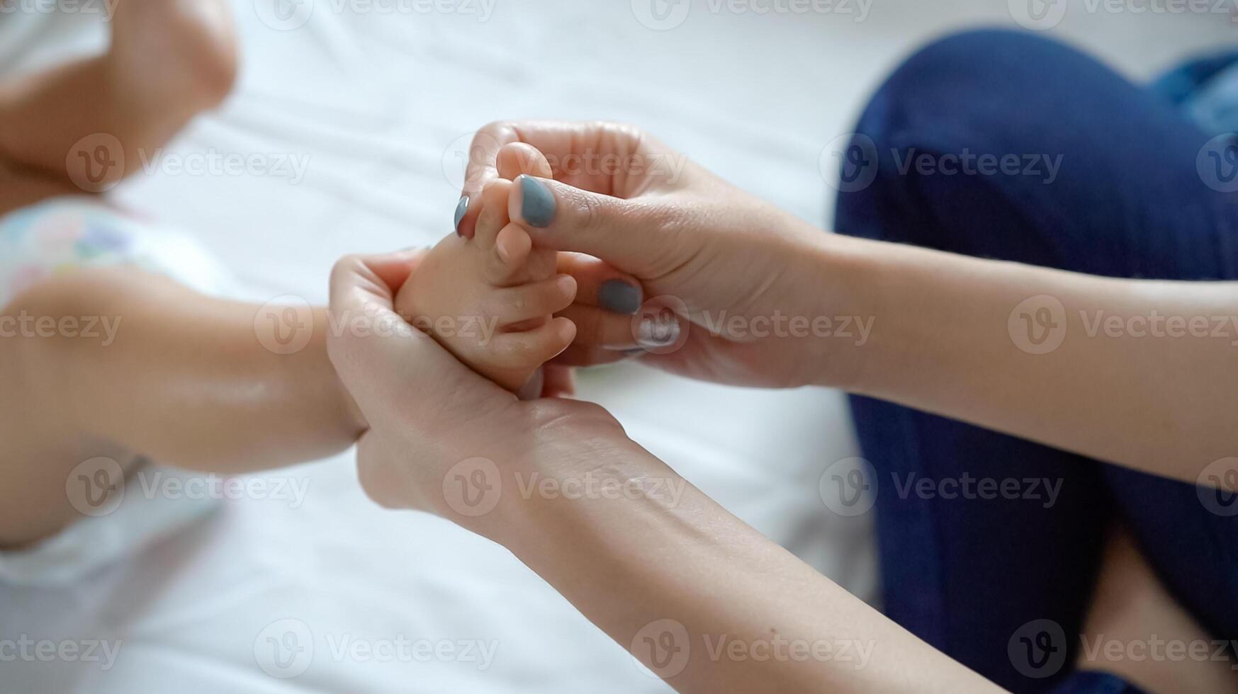 Leg of a newborn in the hands of parents. Newborn baby feet. Little leg of a newborn baby in a big hand of an adult. Baby foot massage. photo