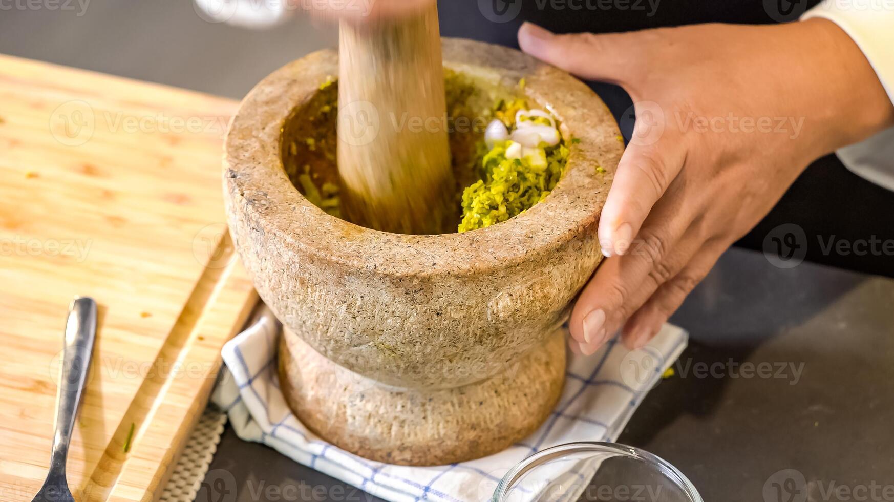 the chef picks up the heavy mortar and pestle, ready to transform a blend of raw spices and herbs into a finely ground Thai green curry paste. photo