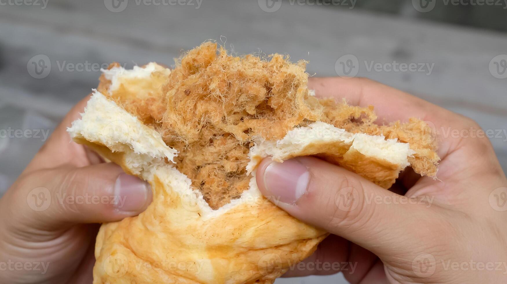 Watch as the man expertly holds and shreds a fluffy bun, revealing the juicy, succulent shredded pork hidden within. The smell of the freshly cooked pork wafts through the air photo