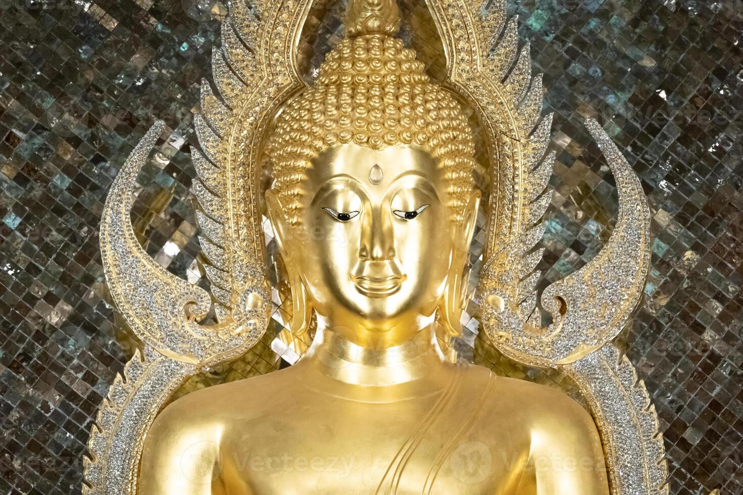 close up of golden Buddha statue is a stunning sight to behold. The intricate details and craftsmanship of the sculpture are clearly visible, showcasing the skill and talent of artist who created it. photo