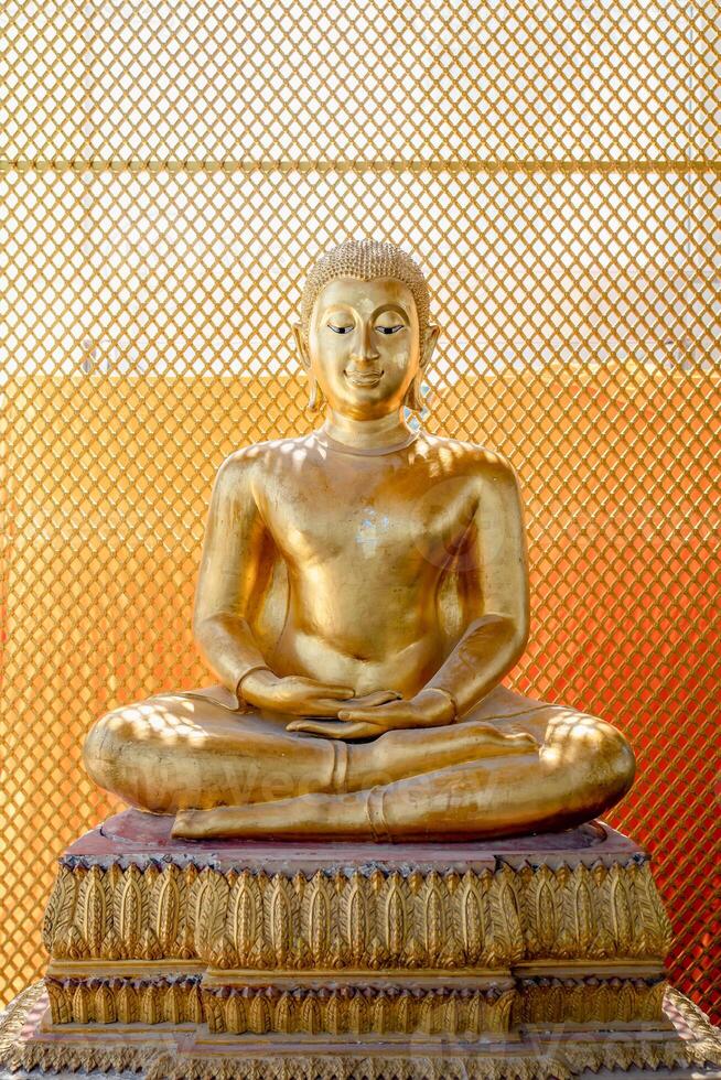 Vintage gold Buddha statue in front of yellow orange grill background with the square pattern light from behind. photo