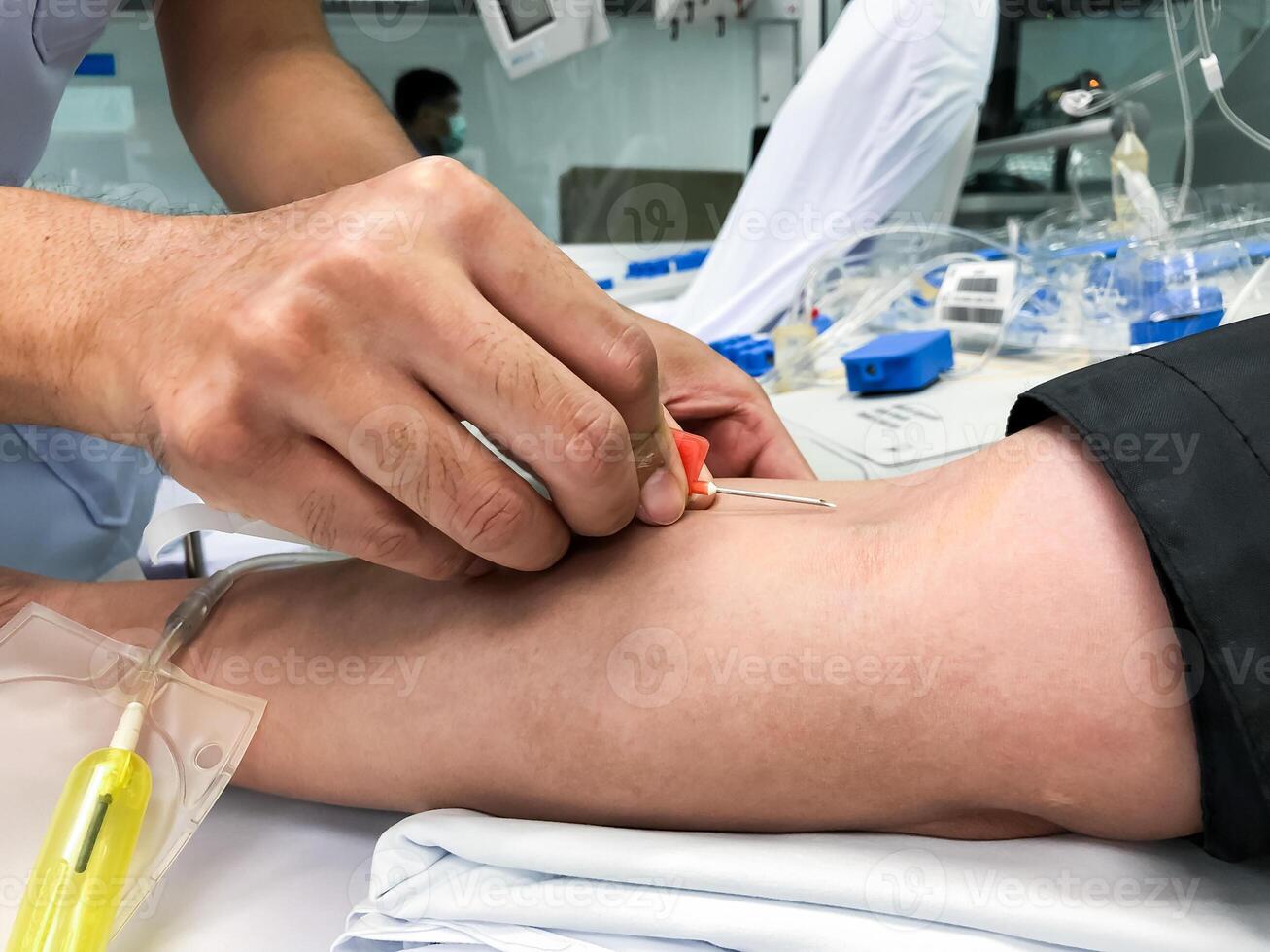Blood platelet donation, a male nurse inserts a needle into donor arm to draw blood at a hospital. photo