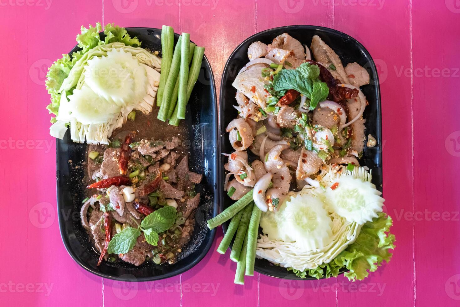 Larb Moo or Thai spicy minced pork salad with entrails and Larb Tub Wan or Thai spicy pork liver salad, a local Isan food in the northeastern part of Thailand, placed on the pink background. photo