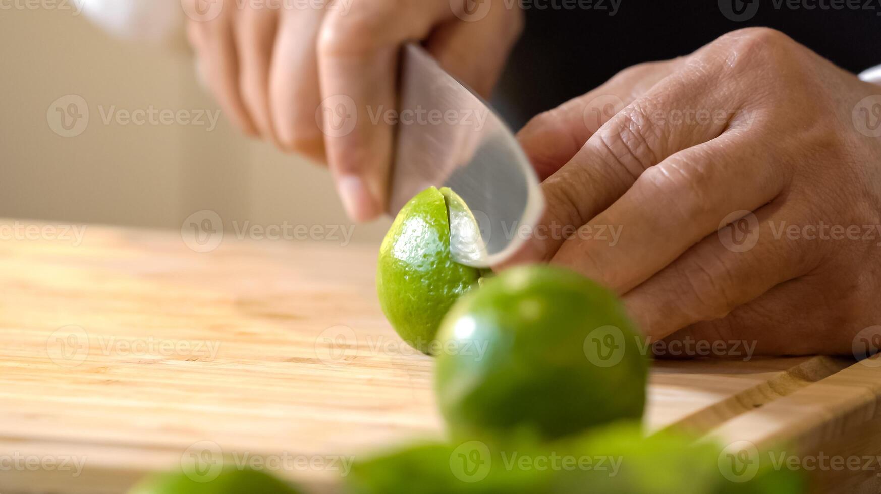 Chef using hands push and roll a lime to juice on a wooden chopping board before cutting and squeezing it. photo