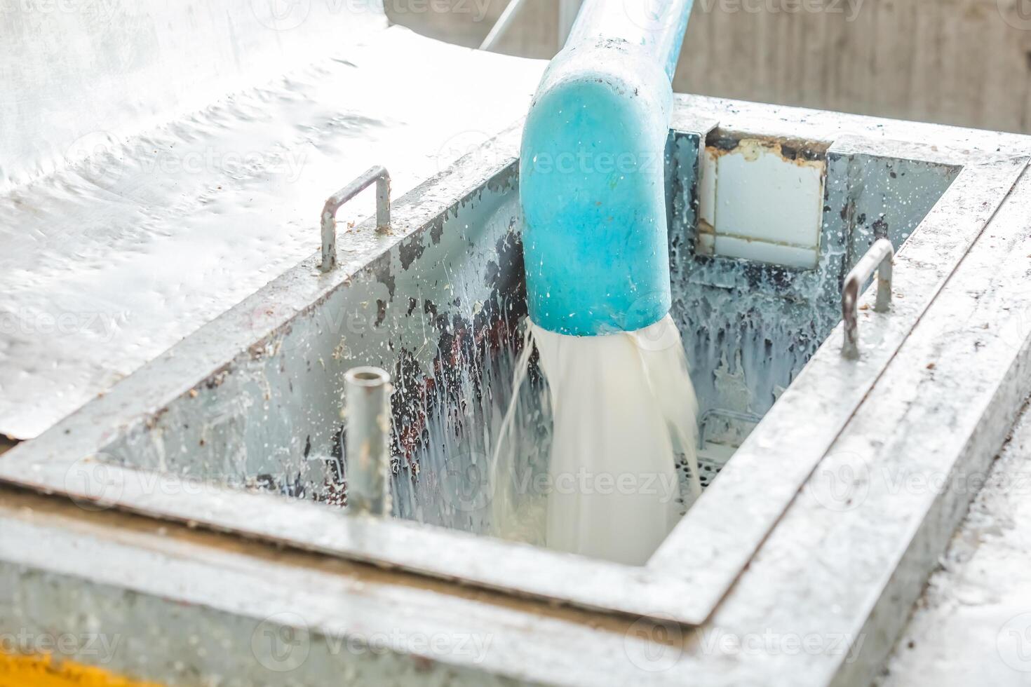 Milky white liquid gush out of the blue plastic industrial water pipe and flow through metal filter. photo