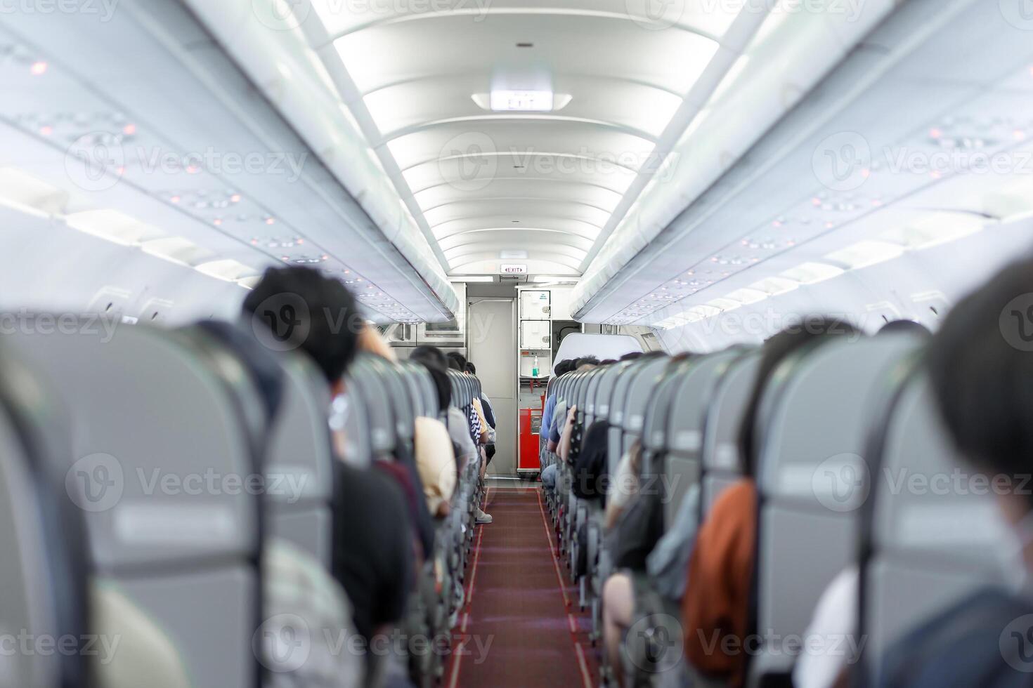 A compact aisle and snug seating within the budget airline cabin, entirely occupied by passengers of Asian descent, prepared for departure. photo