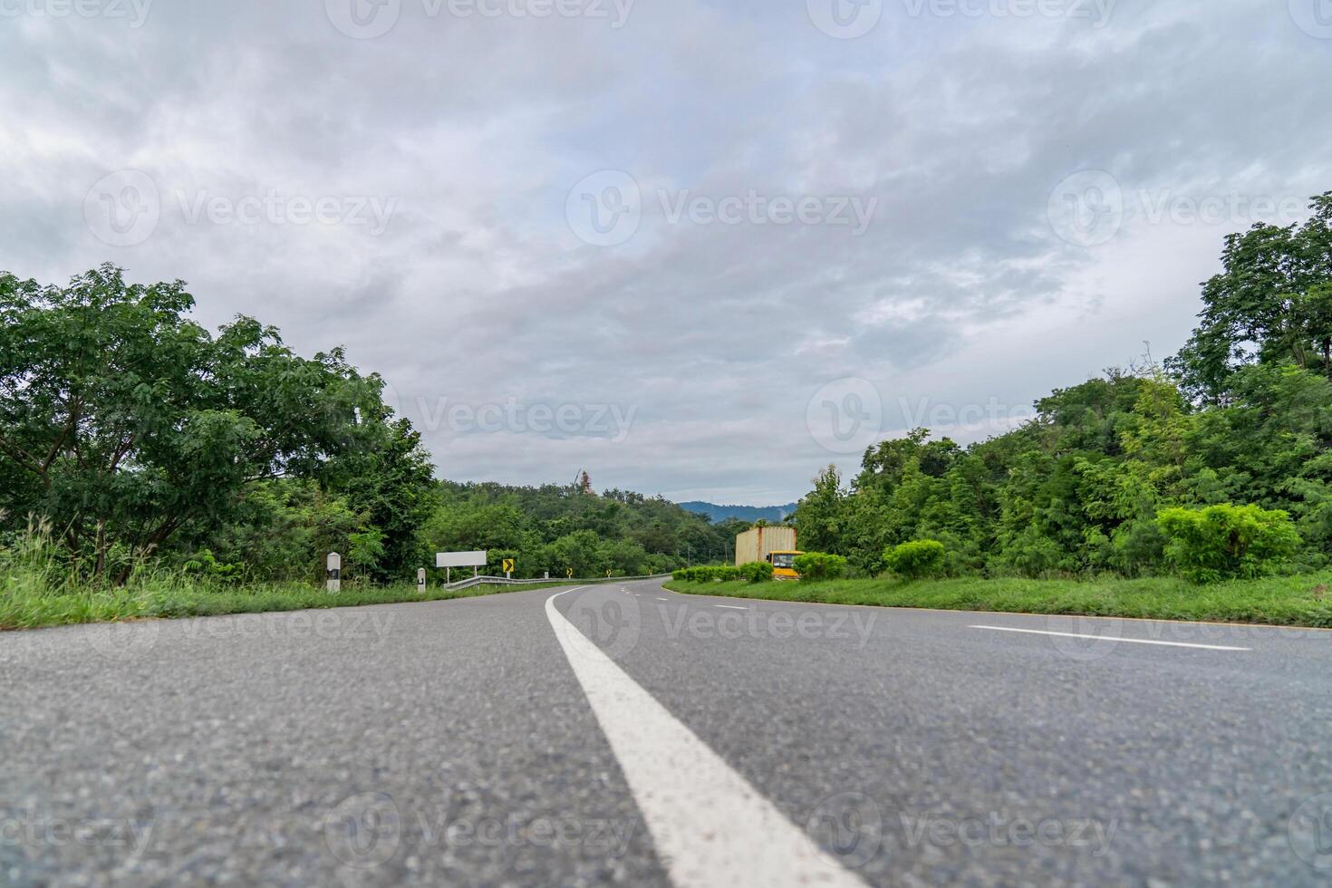 A ground-level perspective of a rural street in Tak Province, Thailand, in open sky during the day. This road serves as key transportation artery to western region of country. photo