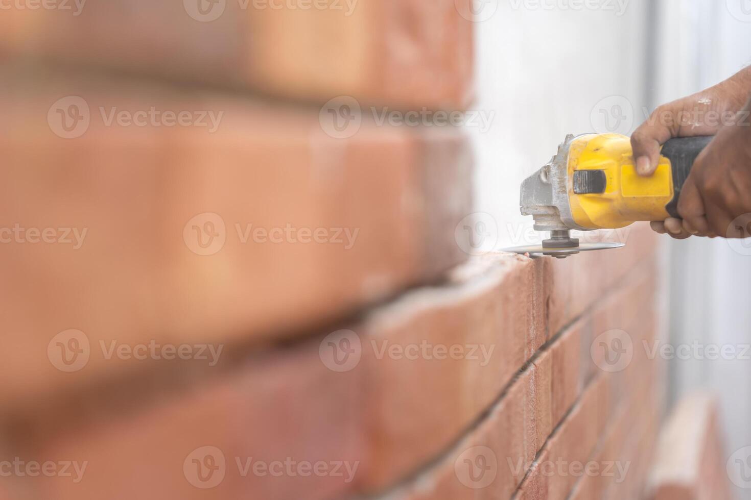 Close up to Grinder Machine in Worker man hand hold saw, grind, check and kept detailed polyurethane foam Brick wall with dust all around. photo