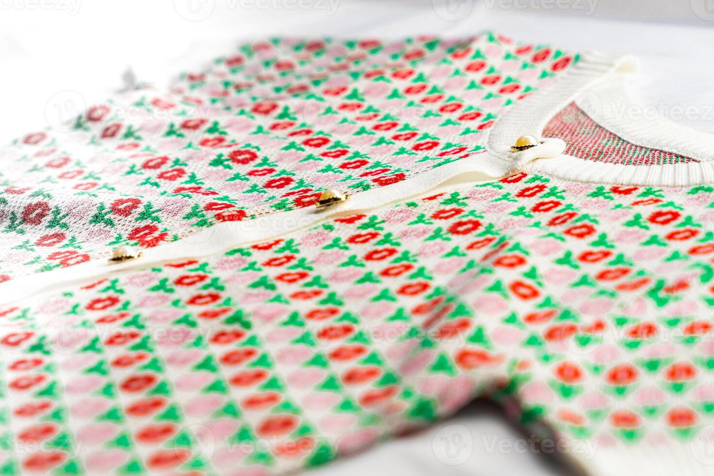 This cardigan fabric has a texture of geometric pattern with colourful red, pink and green tulip flowers. photo