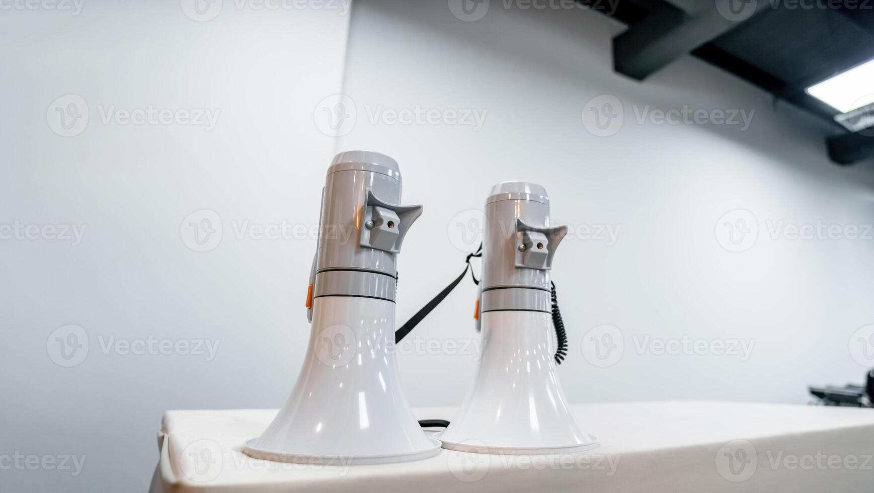 Two white - gray MEGAPHONE are laid on cream table in empty hall, ready to used for event corona virus vaccine booster in Bangkok, Thailand. photo