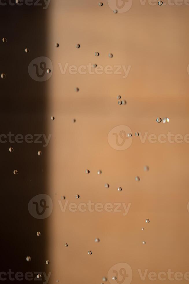Abstract backgrond dropped water stop motion and dripping to the ground from Shower on blur orange brown background at outdoor light. photo