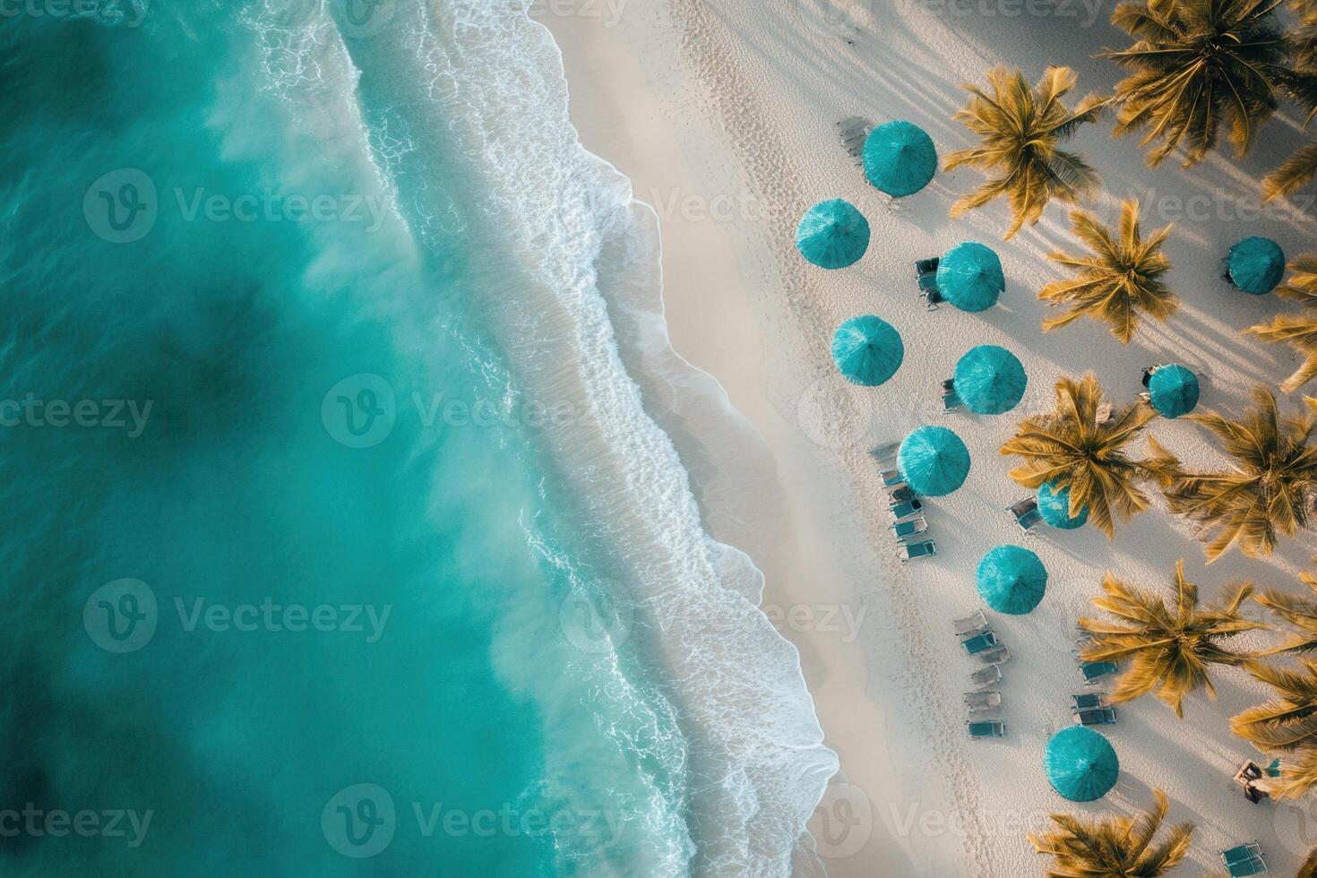 Aerial view of turquoise ocean waves lapping a white sand beach lined with palm trees and blue umbrellas. photo