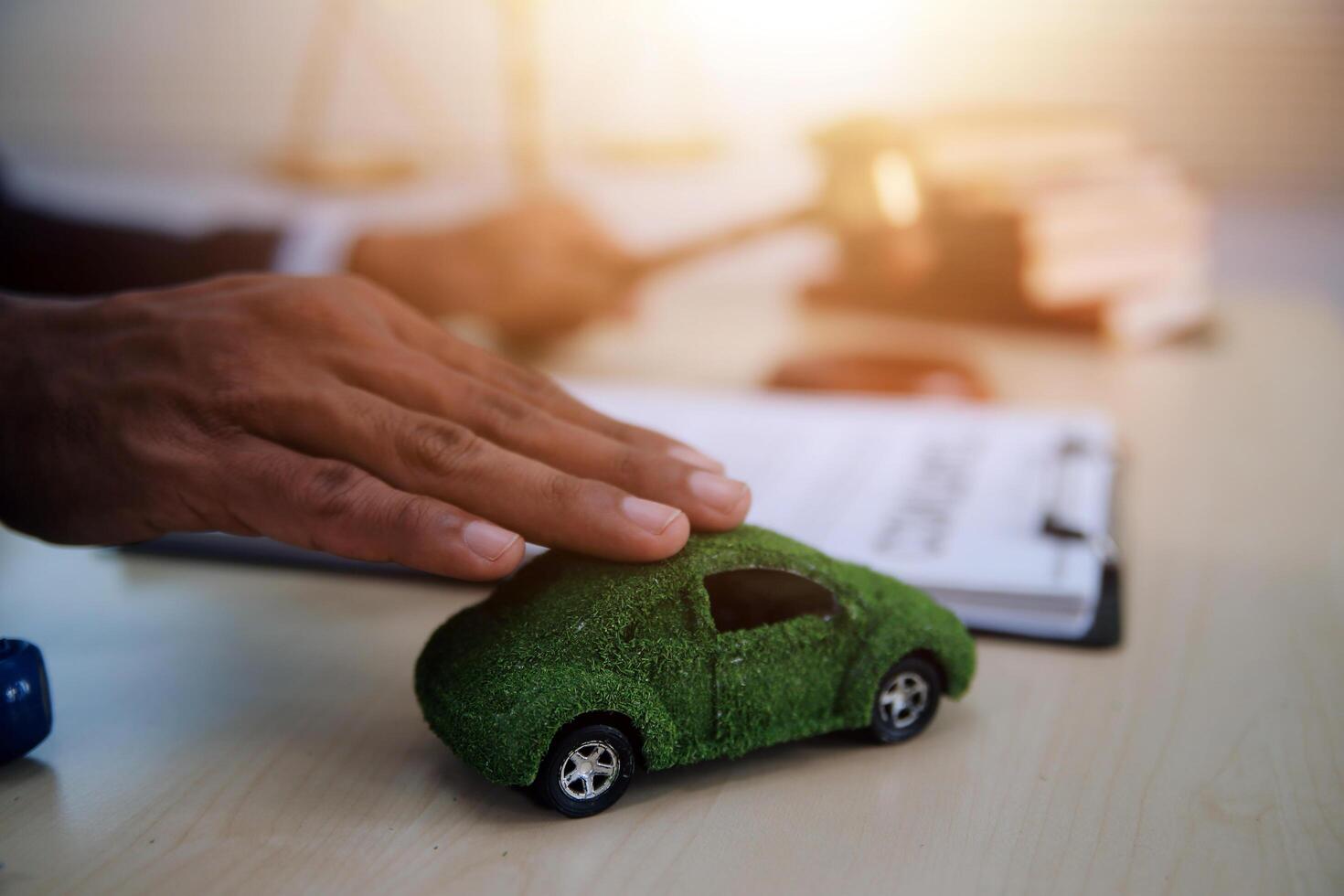 Judge gavel and miniature car symbolize auction or court case against driver who has accident and receiving vehicle insurance payment be on table in front of hands of lawyers. Selective focus photo