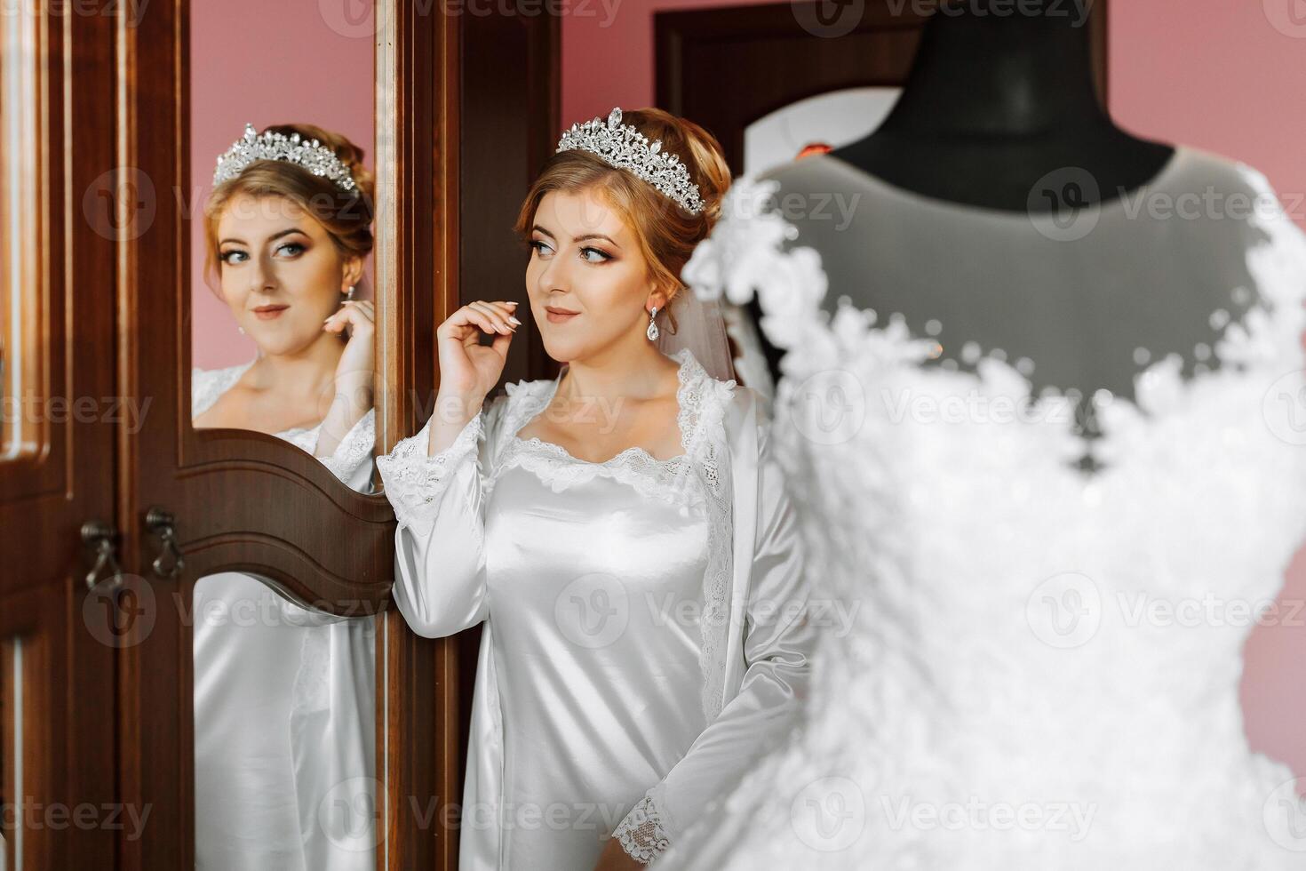 A woman is getting ready for her wedding and is looking at herself in the mirror photo