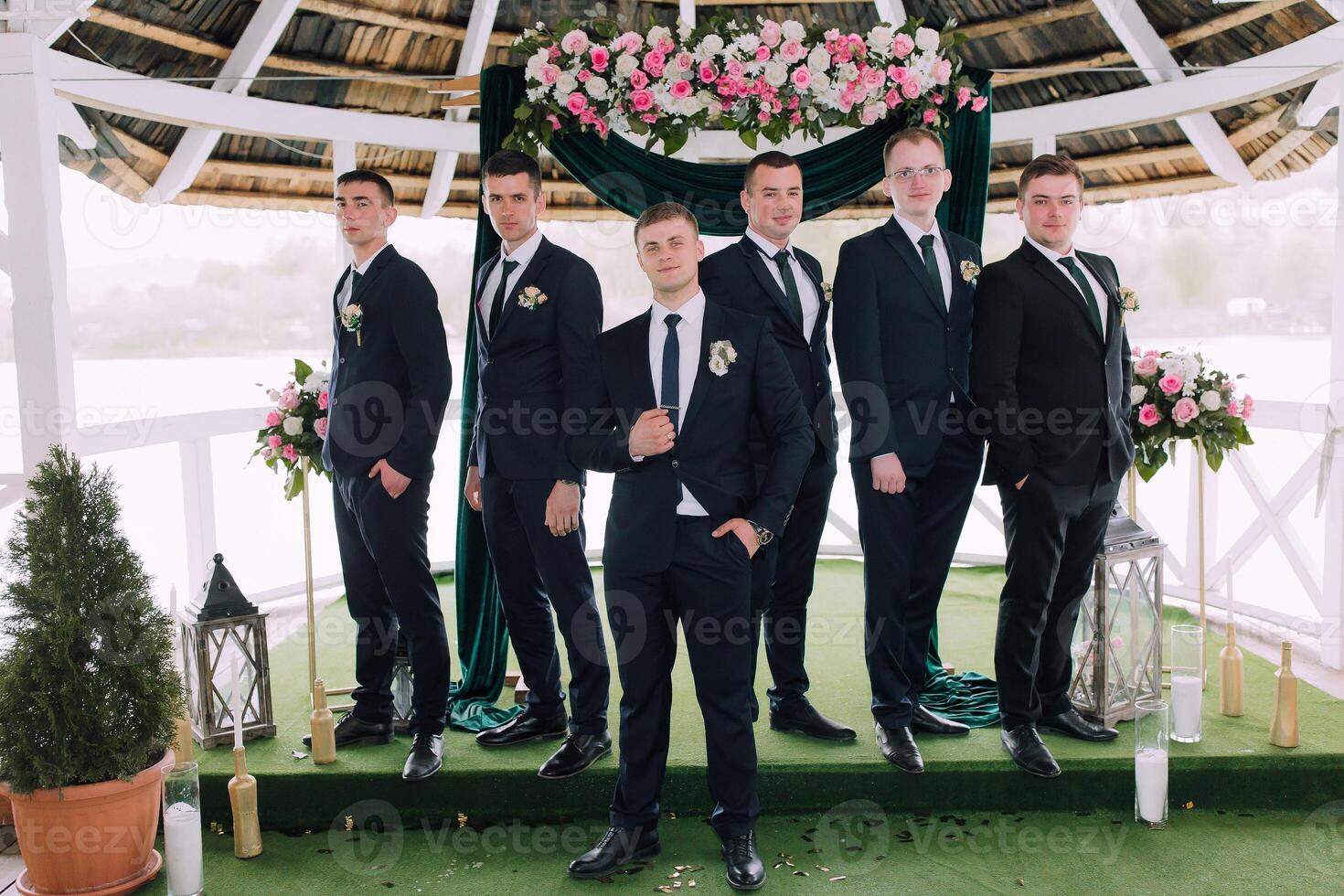 A group of men in suits stand on a stage, posing for a photo