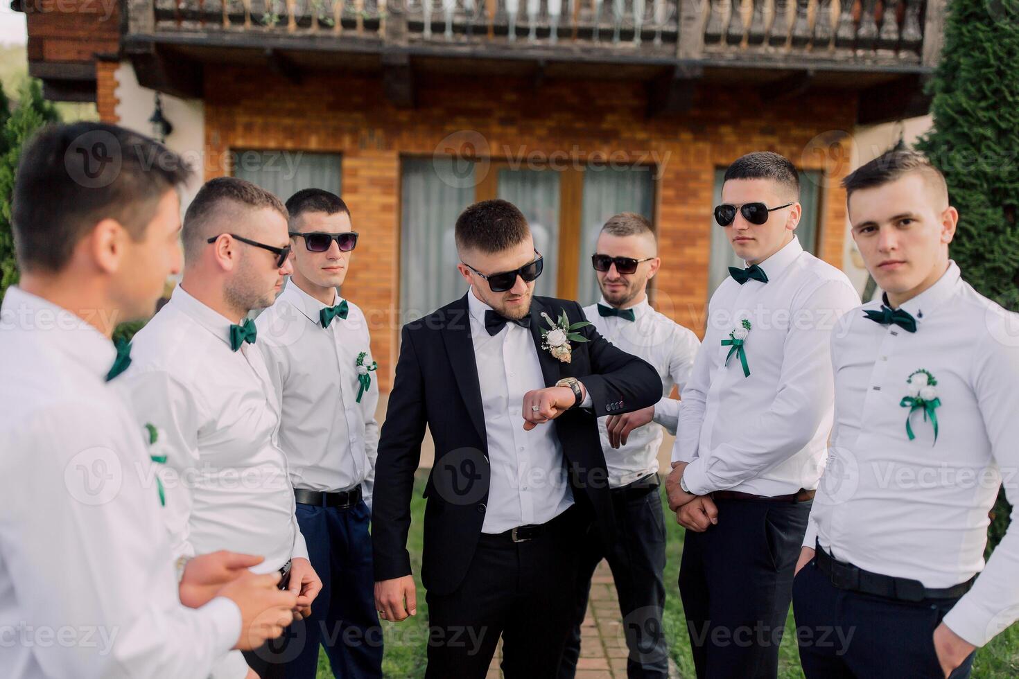 A group of men are standing in a circle, one of them wearing a watch photo