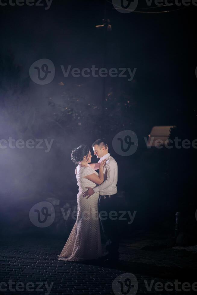 A bride and groom are standing in the rain, embracing each other photo