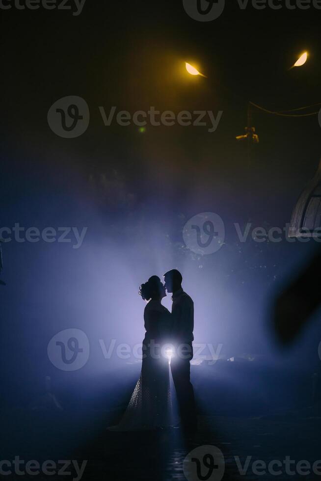 A couple is kissing in the rain, with the man holding a flashlight photo