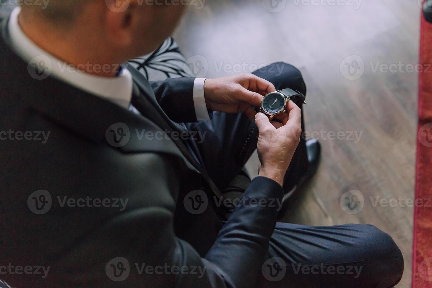 A man in a suit is looking at his watch photo