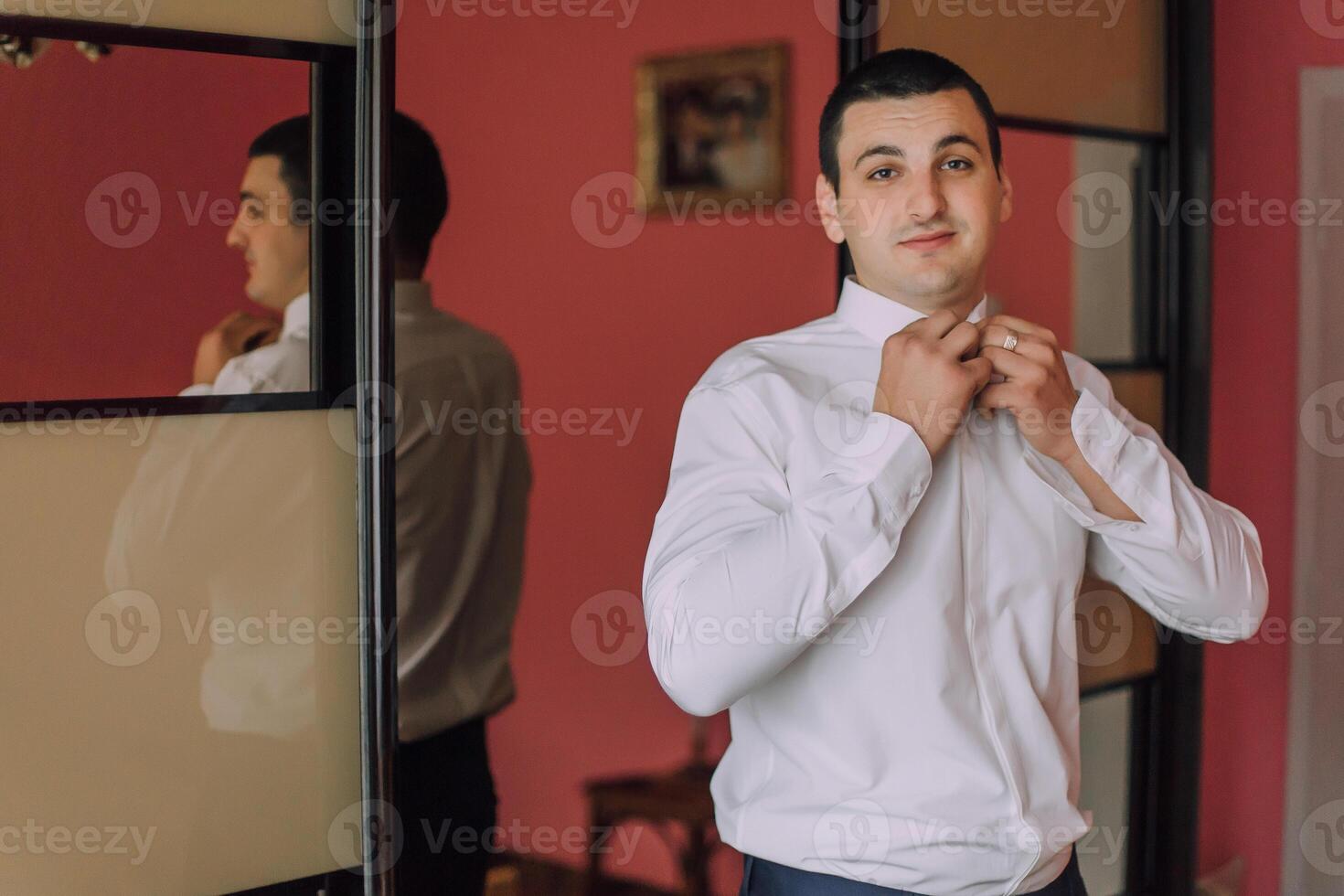 A man in a white shirt is getting ready to dress up photo