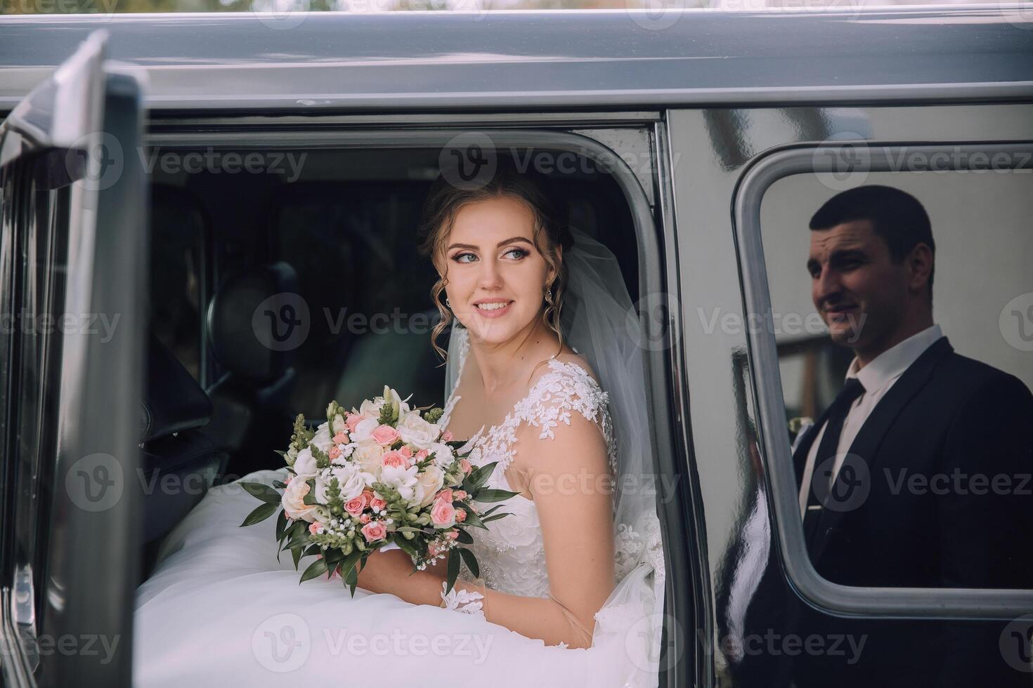 A bride is getting into a limousine with a man behind her photo