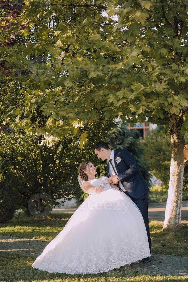 A bride and groom are standing under a tree photo