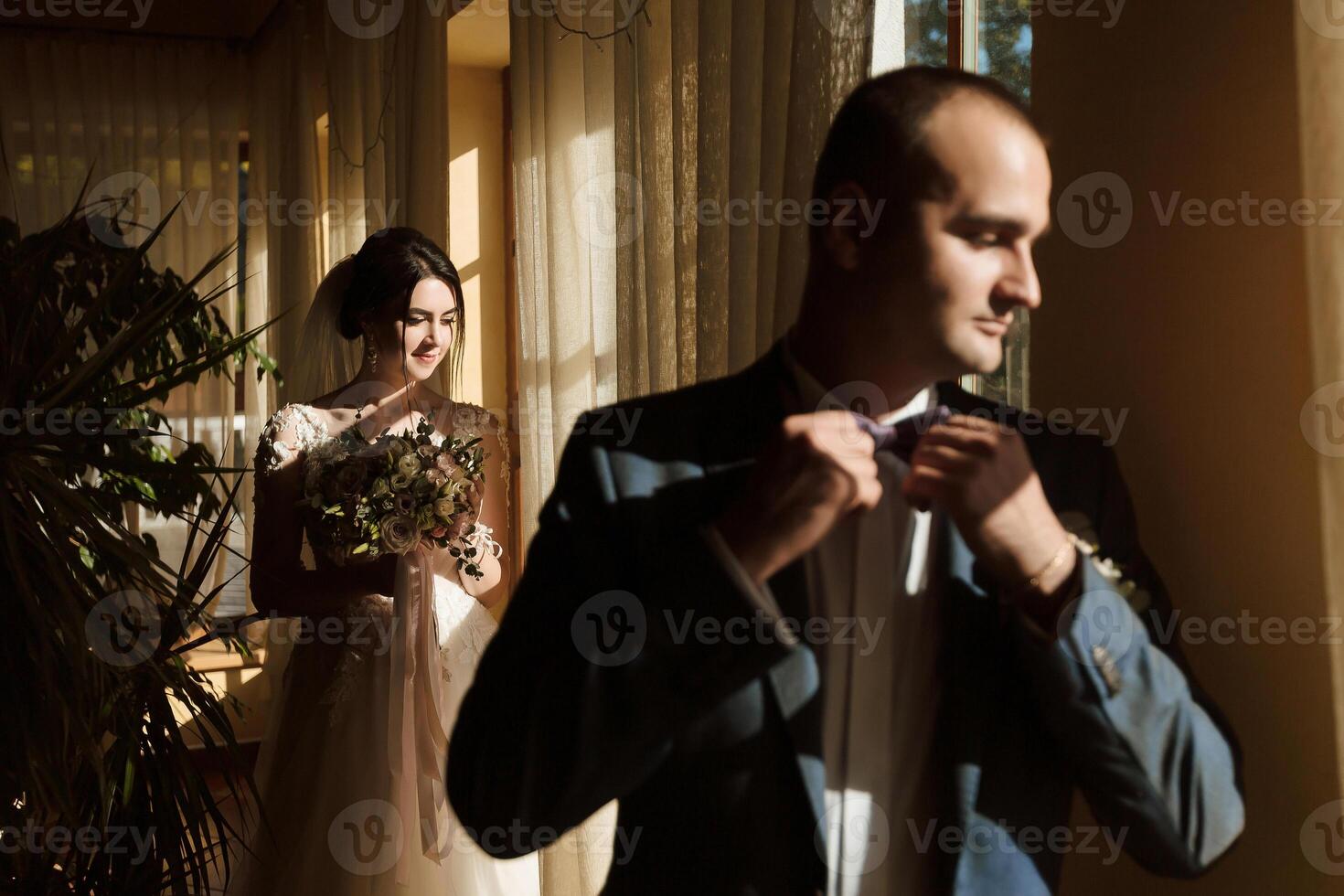 A man is getting ready to tie his tie while a woman stands behind him photo