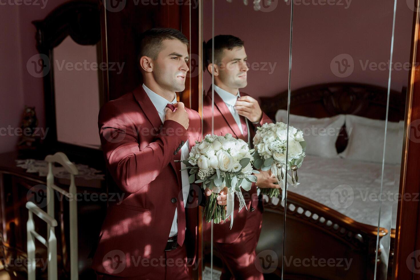 A man in a red suit is getting ready for a wedding photo