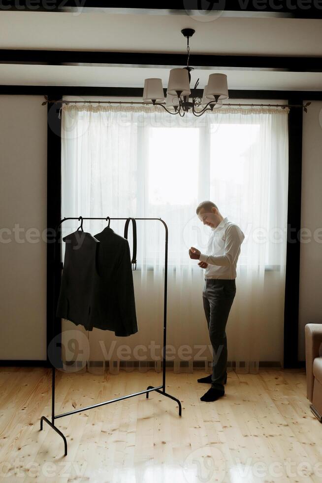 A man is standing in front of a clothes rack photo