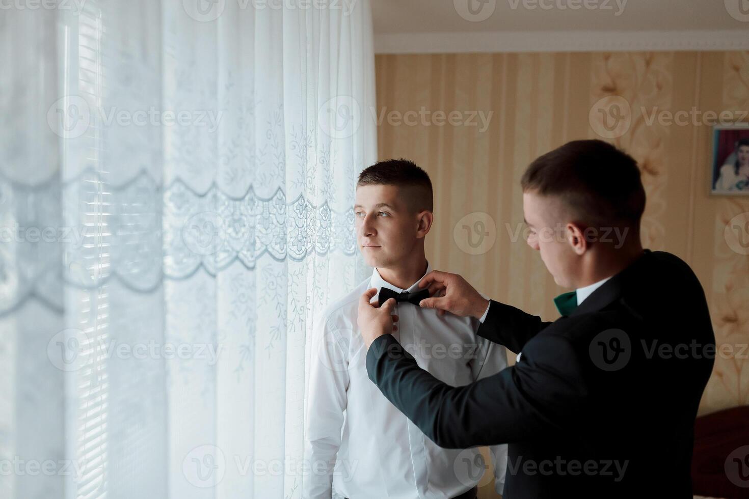 Two men are getting ready for a formal event photo