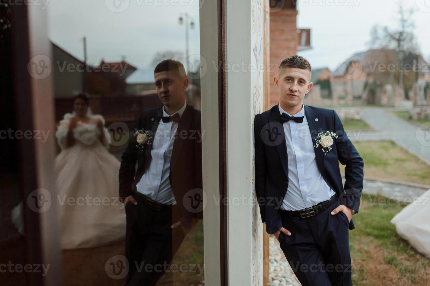 A man in a suit and tie stands in front of a mirror photo