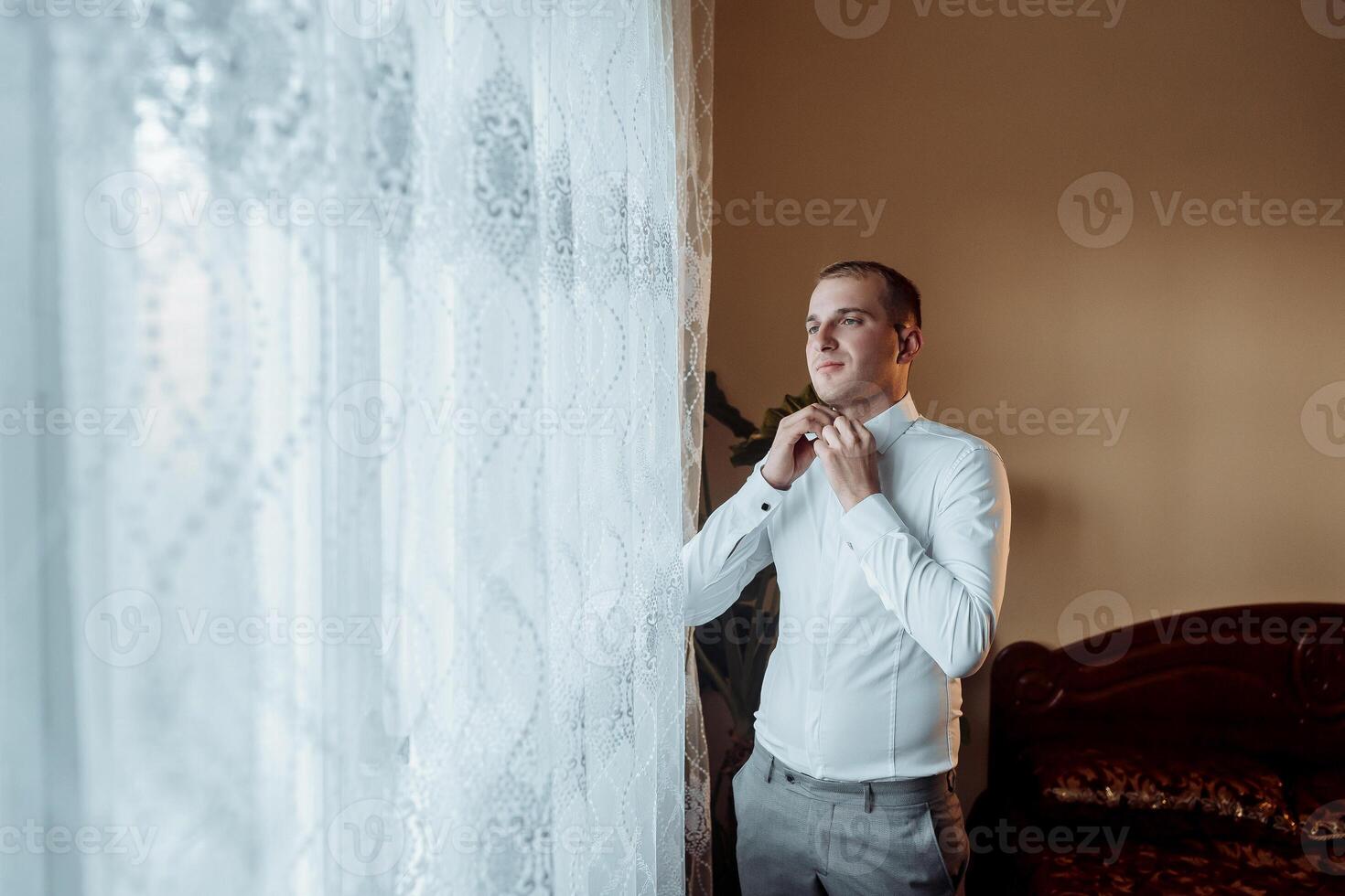 A man in a white shirt is getting ready to tie his tie photo