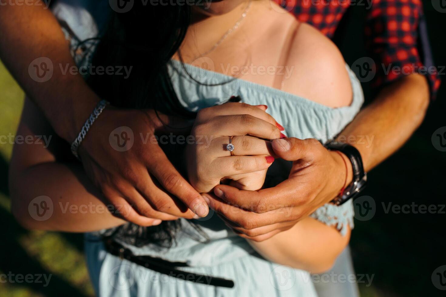 A couple is embracing each other, with one of them holding a ring photo