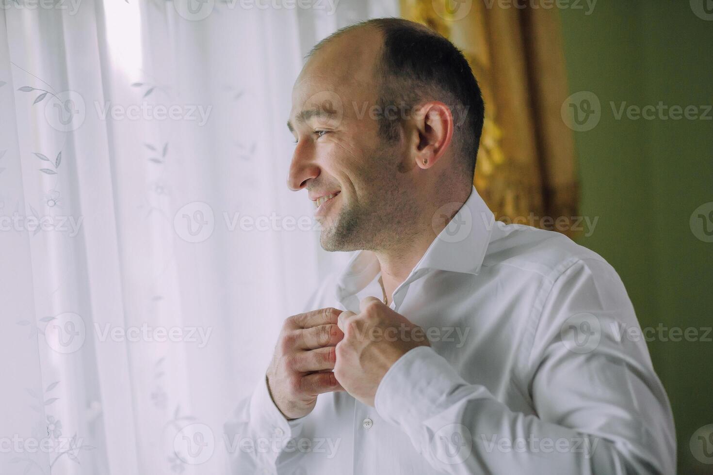 A man is getting ready to go out and is adjusting his shirt photo