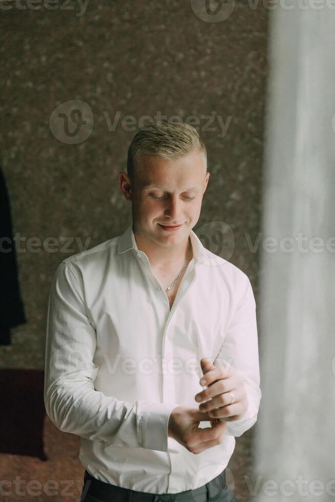 A man in a white shirt is getting dressed photo