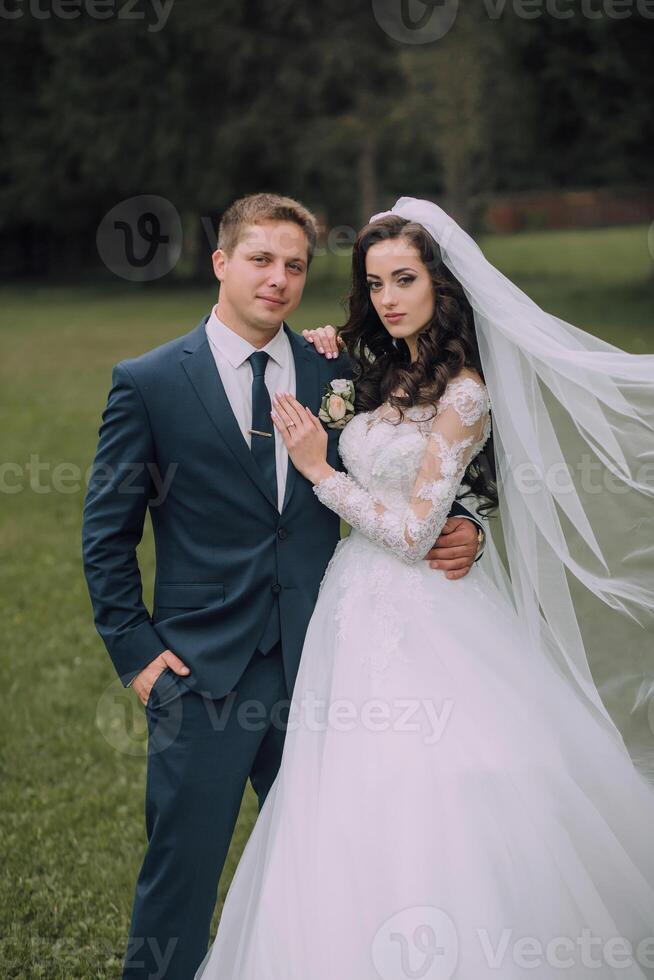 A bride and groom are posing for a picture in a field photo
