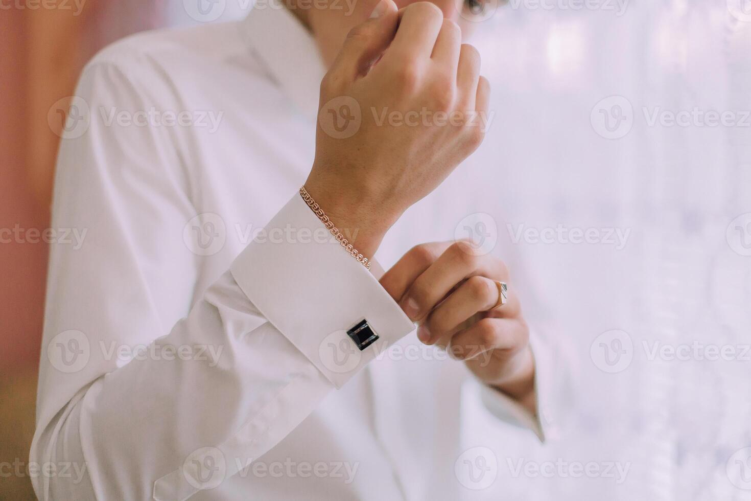 A man is getting dressed in a white shirt and black cufflinks photo