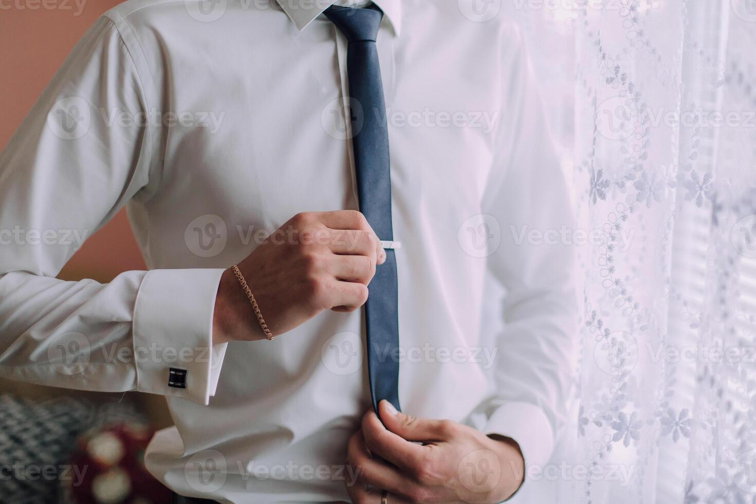 A man is getting ready for work, putting on a blue tie photo