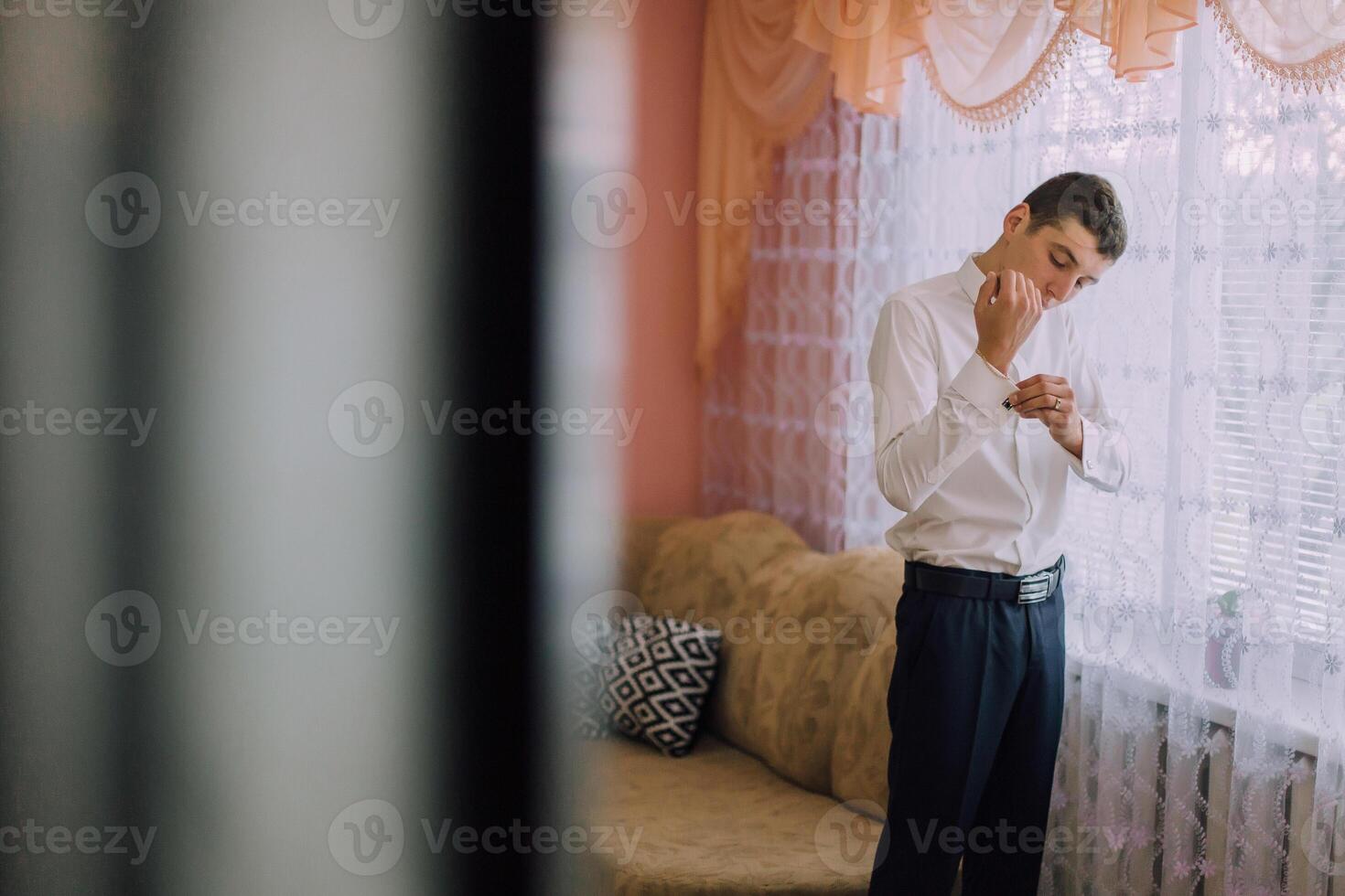 A man is getting dressed in front of a window photo