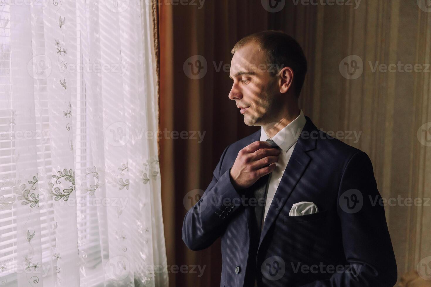 A man in a suit is getting ready to tie his tie photo