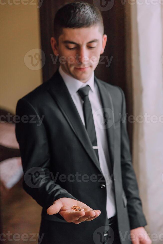 A man in a suit holding a ring in his hand photo