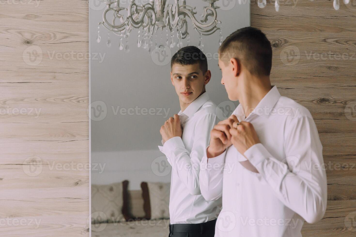 A man is getting ready for a formal event, adjusting his tie and shirt photo
