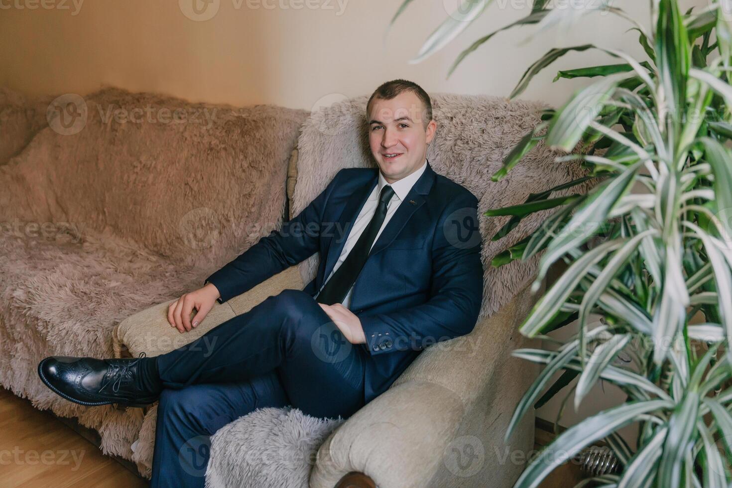 A man in a suit and tie is sitting on a couch photo