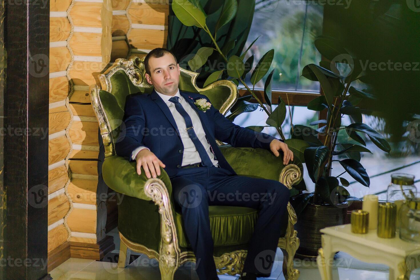 A man in a suit is sitting in a green chair photo
