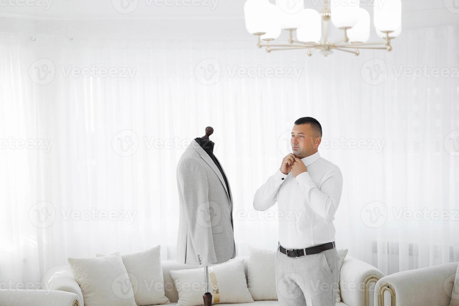 A man is getting ready to tie his tie in front of a mannequin dressed in a strip photo