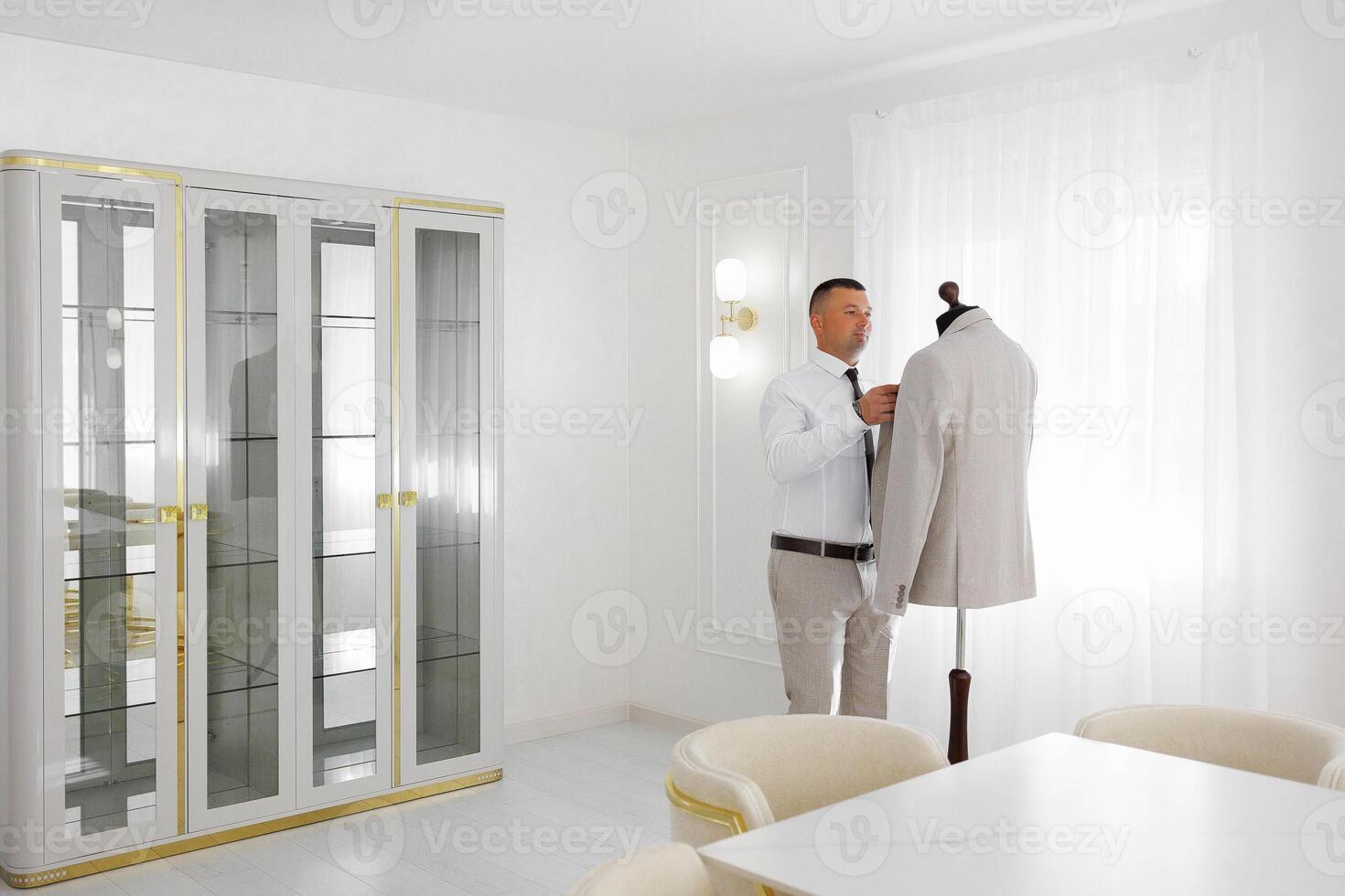 A man is getting dressed in front of a dresser with a mannequin photo