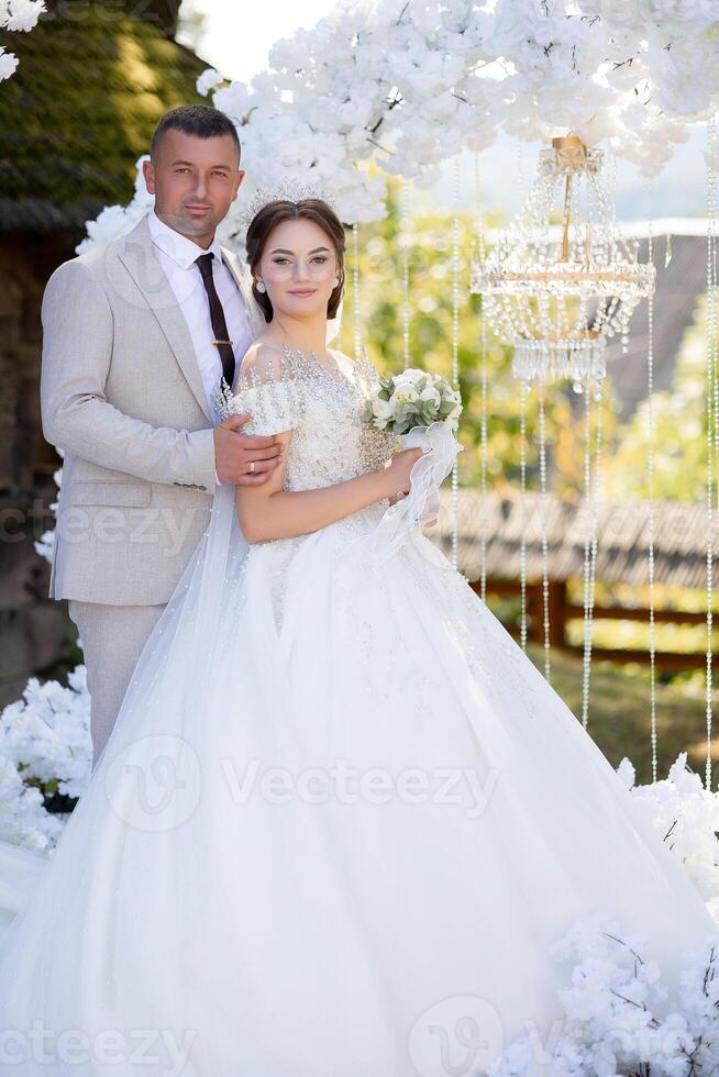 A man and woman are posing for a picture in front of a white archway photo