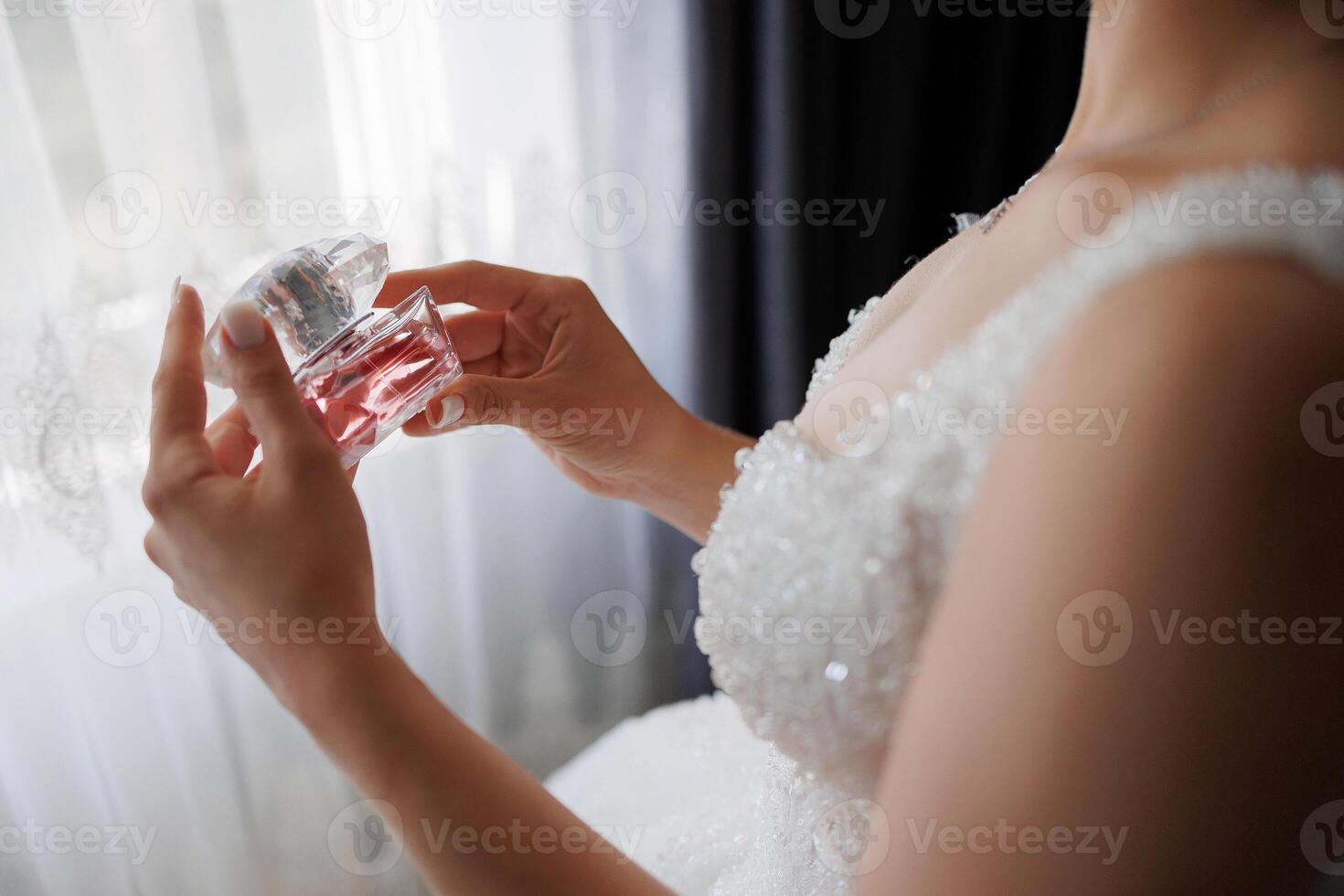 A woman is holding a bottle of perfume and is wearing a wedding dress photo