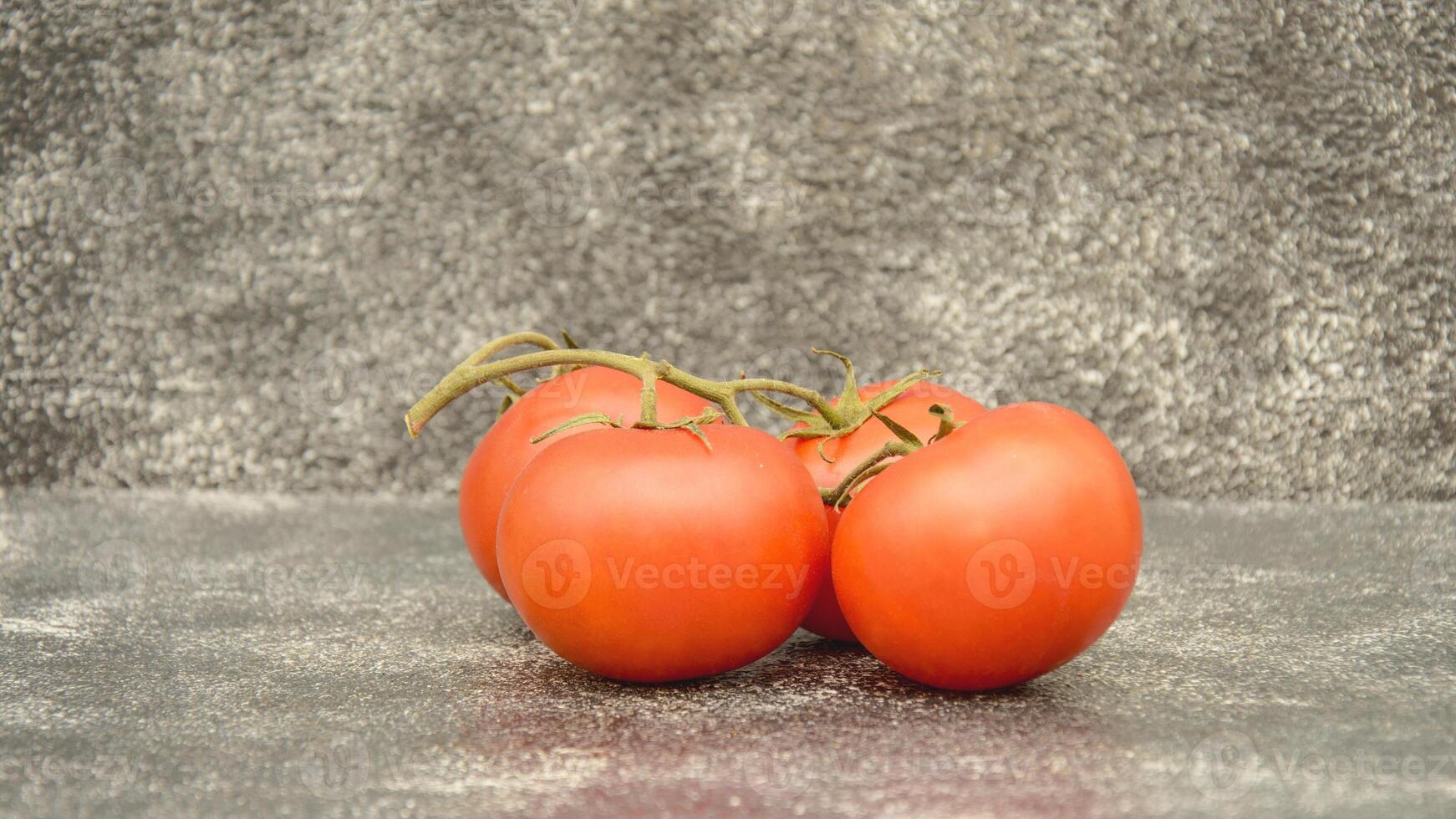 Three tomatoes on a gray background photo