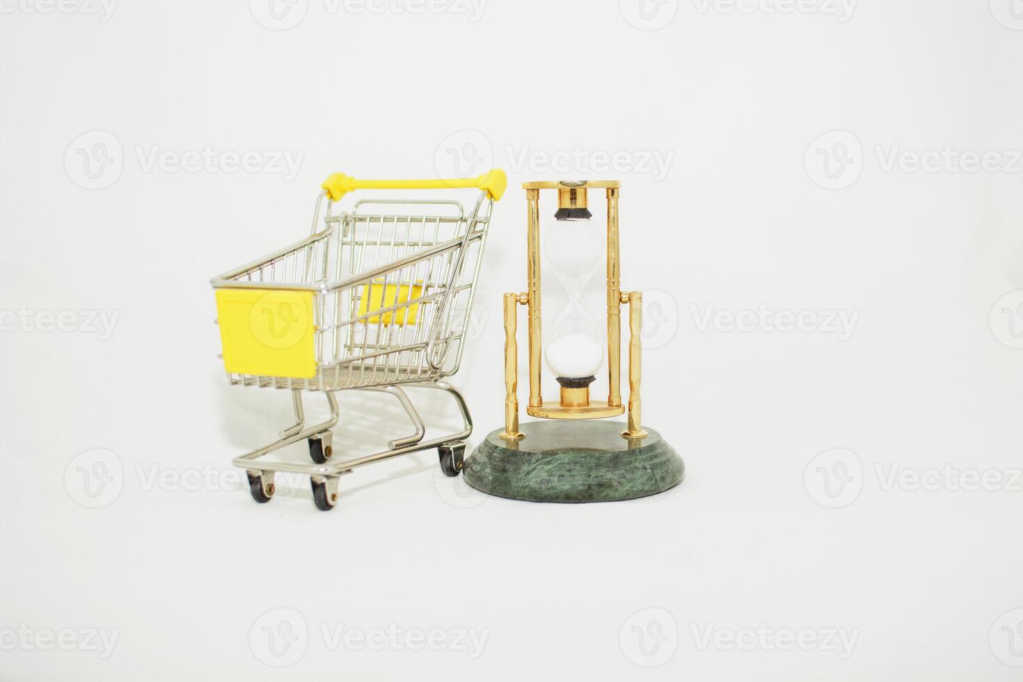 A small shopping cart and a clock on a white background photo